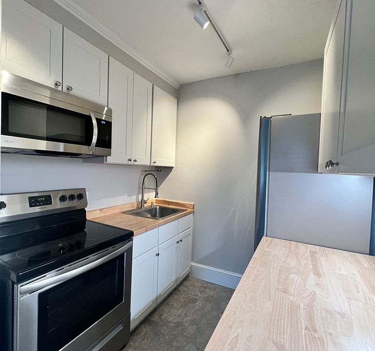 Renovated kitchen with fresh cabinets, butcher block counters and stainless steel appliances