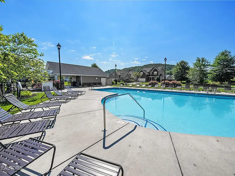 The community swimming pool features plentiful deck chairs for bathing in the sun