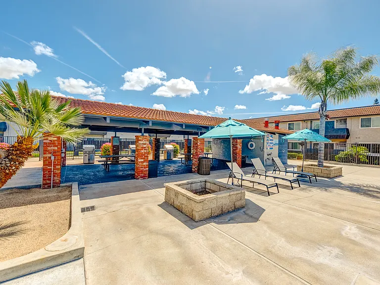 a picnic area with a lounge chairs and umbrellas in front of a building