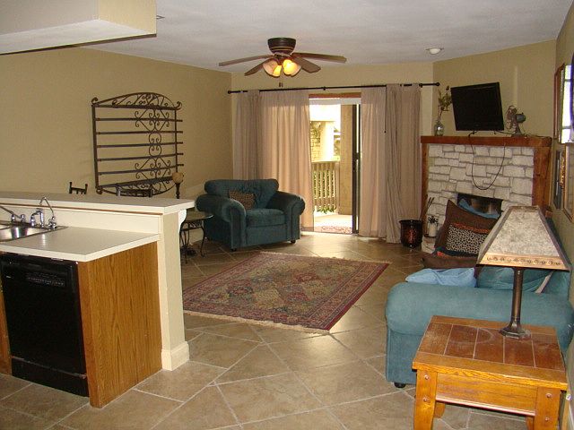 Open living room and kitchen area with fire place and glass doors to the patio.