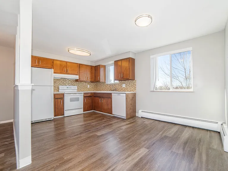 Bright and airy kitchen with modern wooden cabinetry, sleek appliances, and large window for natural light.