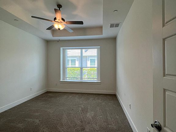 master bedroom features tray ceiling, ceiling fan and large window bench.