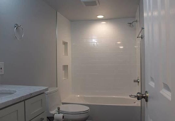 Bathroom with quartz counters and tiled tub with built-in storage niches