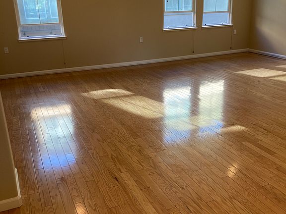 Living Room with hardwood flooring and windows with faux wood blinds