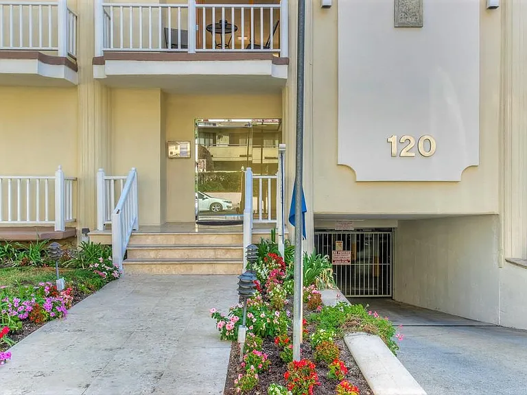 Building entry with beautiful landscaping and gated garage entry.