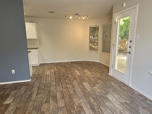 Bright dining area with elegant tile flooring, ample natural light from large windows, and a door leading to the backyard. Features a cozy nook for intimate meals and stylish track lighting