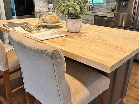 Warm hardwood floors complement light cabinetry and a functional butcher block prep island.