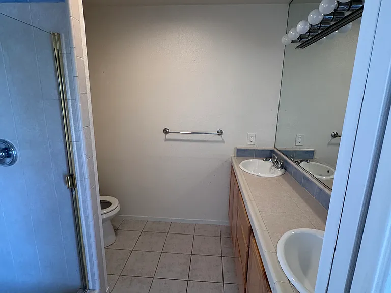 Primary bedroom full bath with two sink countertop, walk-in shower and ceiling heater.