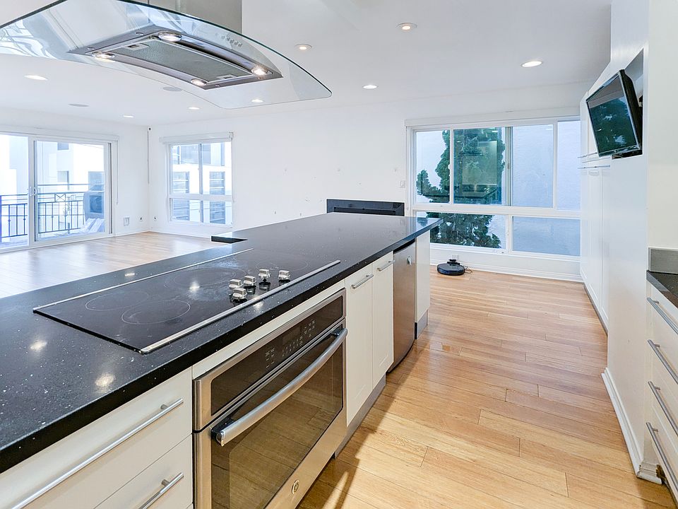 Open layout living room bathing in natural lighting. Modern kitchen with bar and 4 bar stools of 28 Privateer St, unit 4, Marina del Rey, CA 90292 listed by listing agent, Eva Lee with Coldwell Banker Hallmark Realty.