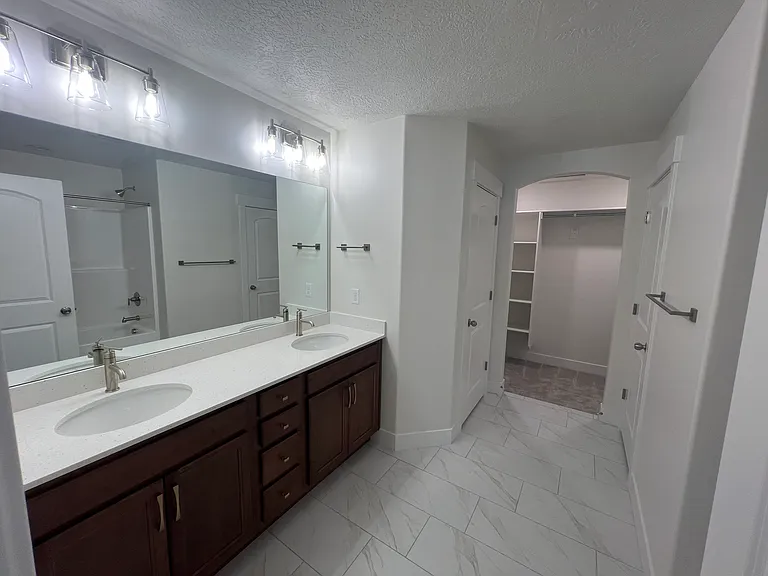 Private primary bathroom with double vanity, linen closet, shower/bath with walk-in closet.