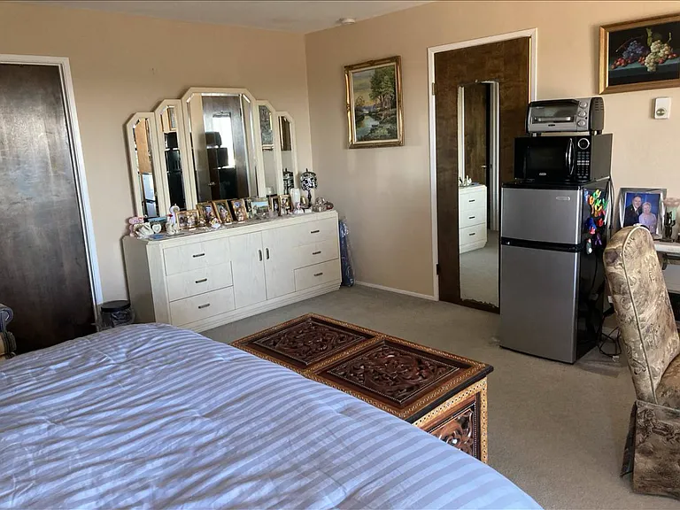 Master bedroom furnished with California king bedroom set, table and plenty of comfortable chairs.