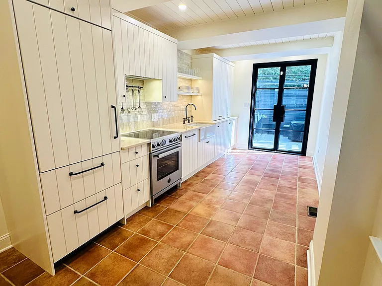 Kitchen with custom cabinets, brand new paneled refrigerator and dishwasher, induction range