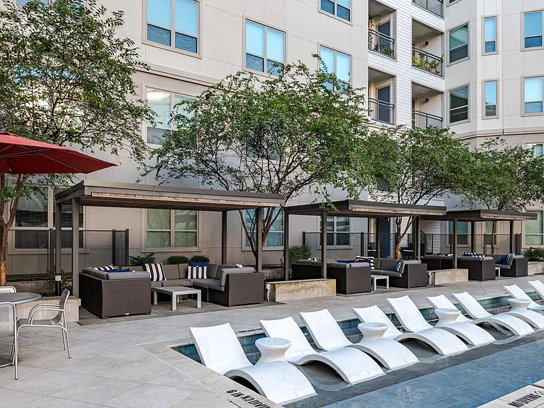 Outdoor Pool Area with Modern Chaise Lounges and Shaded Seating