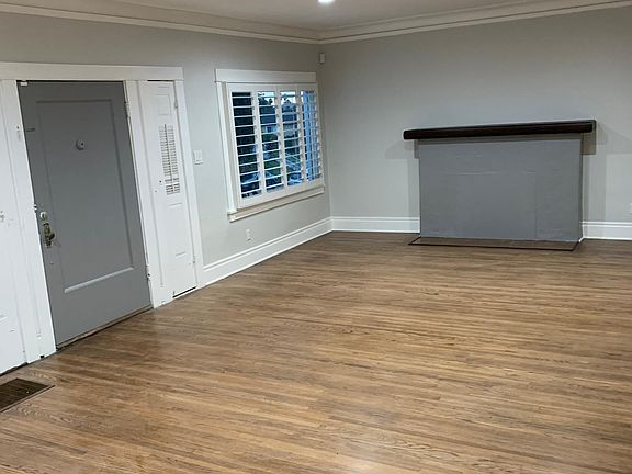 View of living room with hardwood floors, plantation shutters, and modern recess lighting.