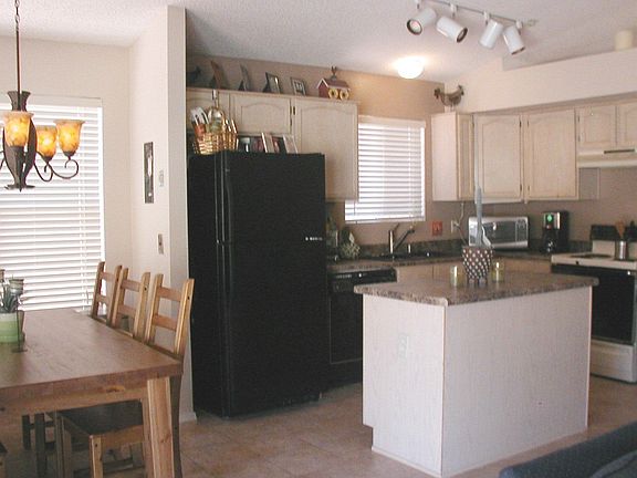 Vaulted island kitchen has tile flooring and is open to the family room.