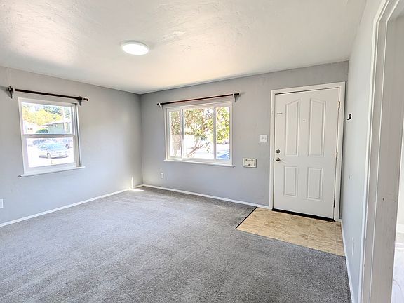 POV from hallway looking at the living room and front door. The kitchen in on the right