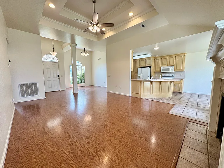 Open living area with soaring tray ceiling, recessed lighting, and ceiling fan _ flows directly into kitchen