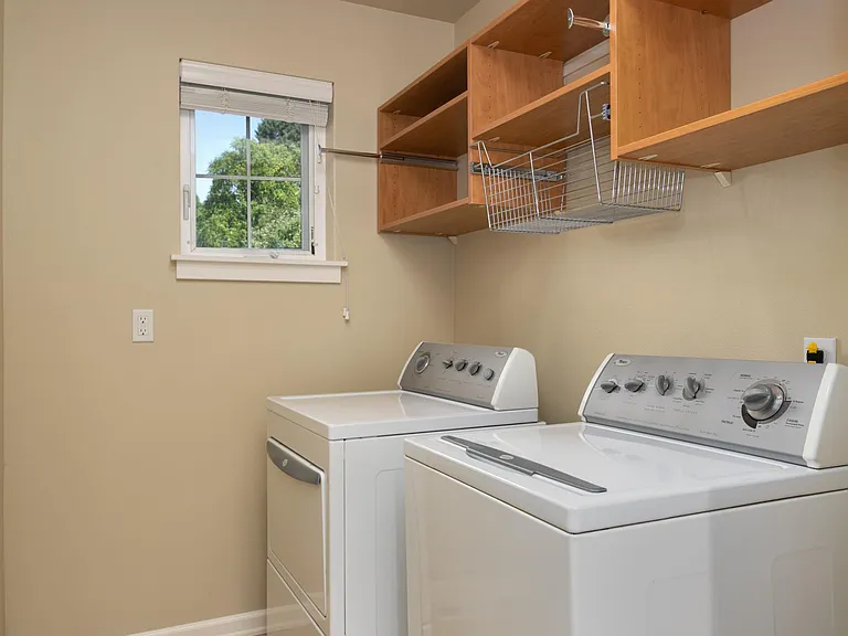 Laundry room with full size washer and dryer and overhead built-in shelving.