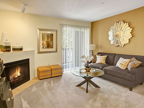 Living room with couch, coffee table, fireplace, and sliding glass door leading out to the balcony