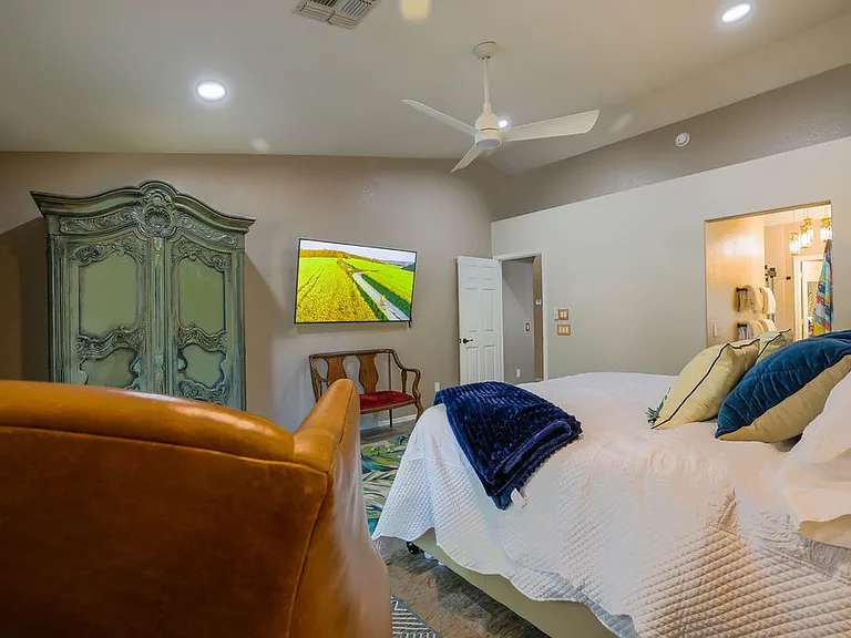 Master suite bedroom with king size adjustable split NECTAR hybrid copper cooling mattress, side tables with outlets, side seating, 60" TV, amoire, dedicated bath, walkin closet, with french doors to back patio