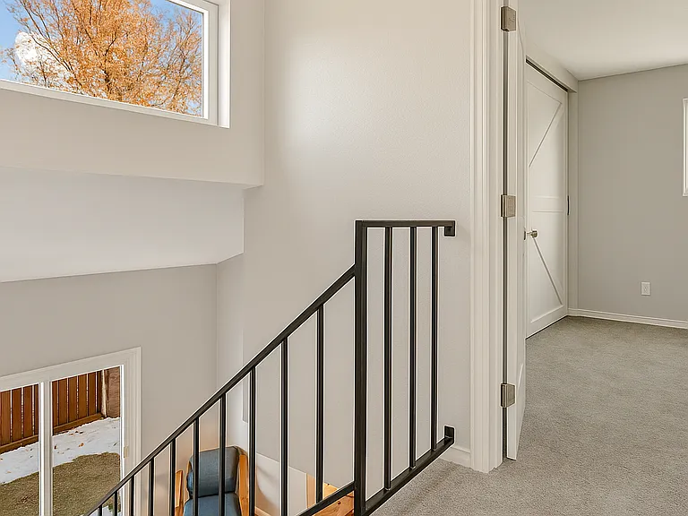 Bright and airy stairway landing with large windows that bring in natural light, creating a warm, welcoming transition between levels.