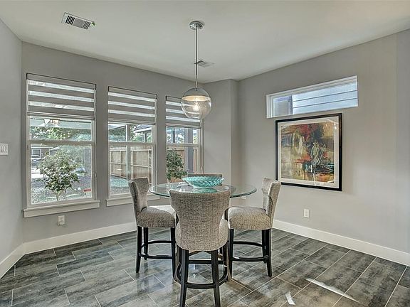 Spacious dining room has tile floor with Craftsman-style baseboards, and custom shades (on all windows throughout the home).