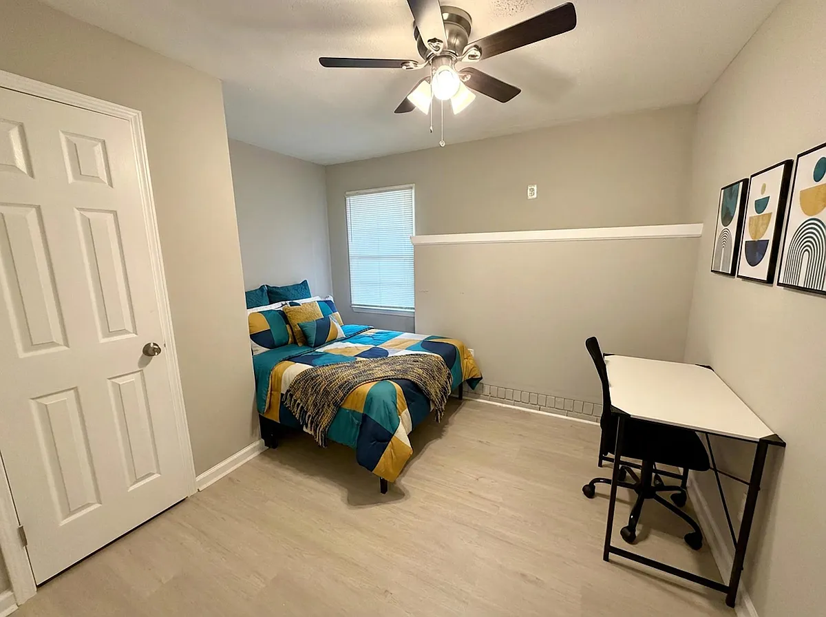 Photo 1 of 3 - Dogwood Dr NW - Lawrenceville, GA Furnished bedroom with a full bed, ceiling fan light, and a dedicated desk workspace beside a window with blinds. - Dogwood Dr NW
