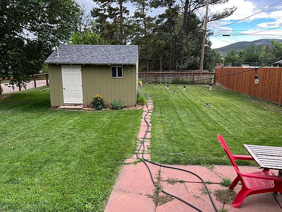 Fully fenced backyard with stone patio and storage shed.