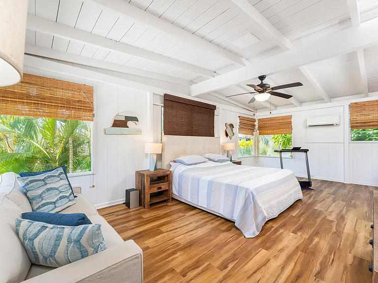 Detached studio featuring vaulted open-beam ceilings, split AC, and flexible space for sleeping, lounging, or a private workspace. Large windows bring in natural light and tropical garden views.