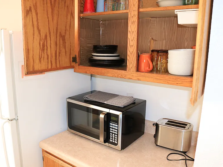 kitchen cupboard is stocked with bowls, plates and cups
