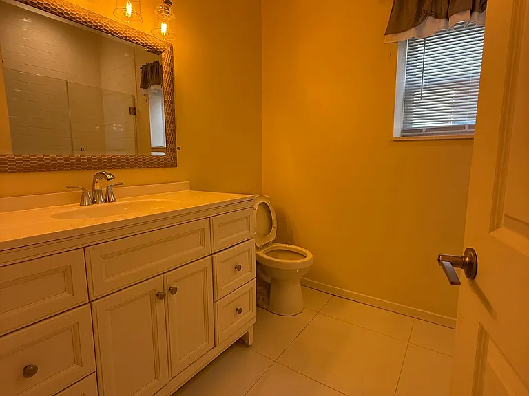 Spacious bathroom with a wide vanity, ample drawer storage, framed mirror, and a window for natural light.