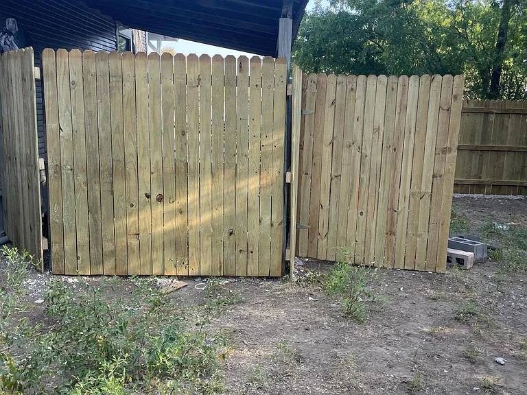 Wood fence in backyard. On the other side of the fence is the carport