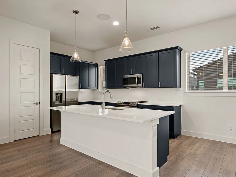 View of kitchen with very functional and esthetic island, windows with more natural light, and pantry on the left.
