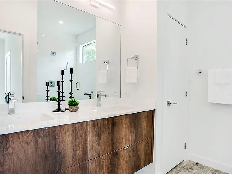 Dual vanity with wood-finish cabinetry, white countertop, and polished chrome fixtures