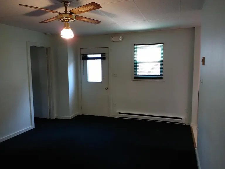 Living room looking towards front door. Nice ceiling fan. Mini blinds (matching with carpet) throughout living room and bedroom.