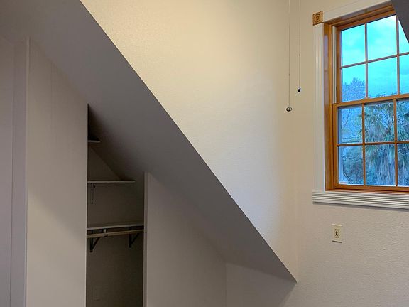 upstairs bedroom with custom window, closet and ceiling fan