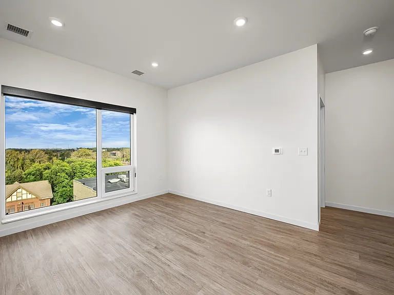 Bright room with elegant hardwood floors and a large window offering stunning views of lush greenery and blue skies. Bright room with elegant hardwood floors and a large window offering stunning views of lush greenery and blue skies.