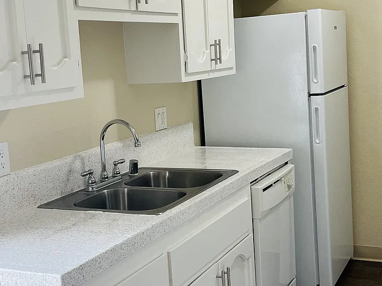 Kitchen with white cabinets and appliances at Plaza Verde Apartments in Escondido, California.
