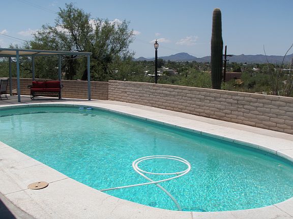 Pool in the backyard with a tennis court below.