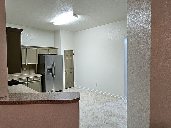 Kitchen area, with new tiles, kitchen cabinets and a fridge. Well lit and spacious.