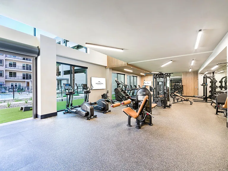 Floor-to-ceiling windows and open views of the pool bring natural light into this well-equipped fitness studio designed for all workout styles.