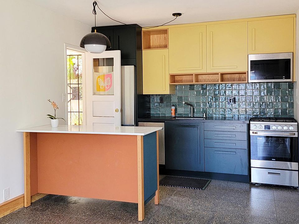 The kitchen has custom cabinet faces and open shelves. And an island with space to tuck in 2 stools. There is an overhead pendant and under cabinet lighting.