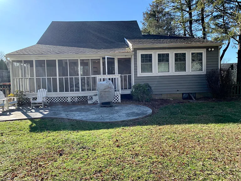 Rear view of home complete with patio, grill and some chairs.