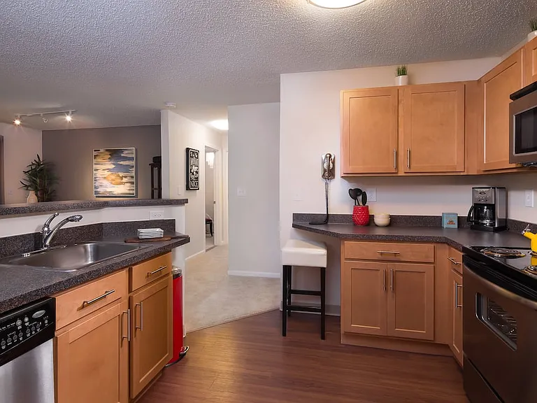 Classic Package kitchen with stainless steel appliances, black speckled laminate countertops, maple cabinetry and hard surface flooring