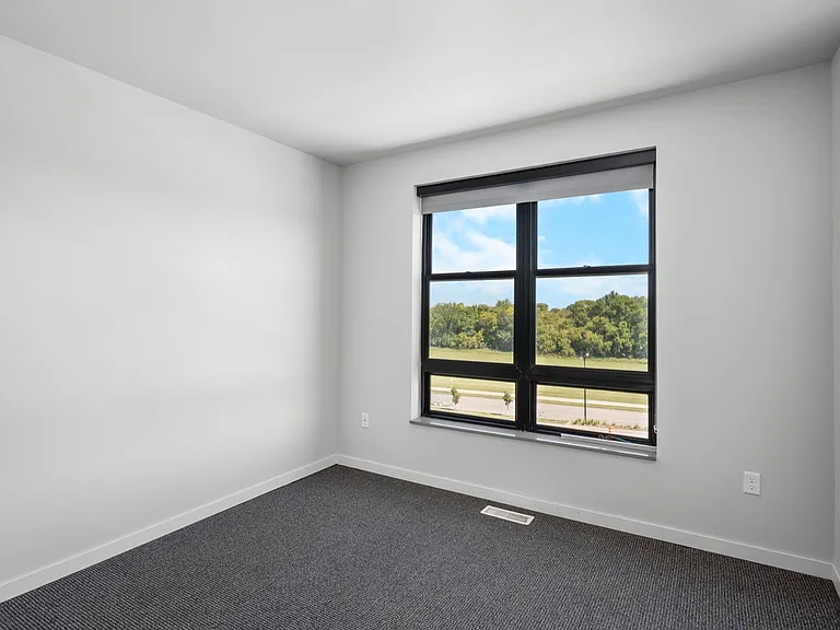 Bright, spacious bedroom with a large window offering stunning views of lush greenery and blue skies. Bright, spacious bedroom with a large window offering stunning views of lush greenery and blue skies.
