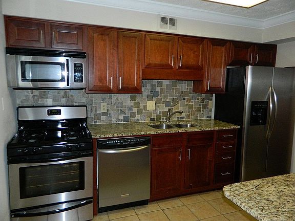 Renovated kitchen with stainless appliances, granite counters, and cherry cabinets