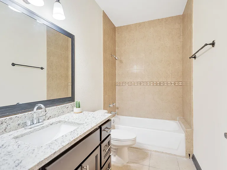 Interior of a bathroom in Merida Vista Apartments, Laredo, Texas, showcasing a tub, sink, and wall mirror
