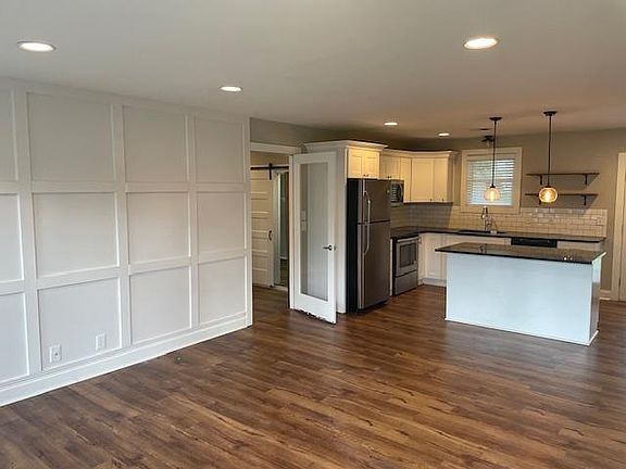 Looking in from front door, living room and kitchen, glass door leads to bonus room, laundry room, and side door to driveway.