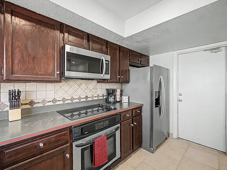 Efficient kitchen with ample wood cabinetry, tile backsplash, and stainless steel appliances for everyday cooking.