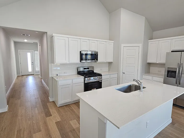 A chef's dream! This modern kitchen features crisp white cabinetry, stainless steel appliances, and a massive granite island.